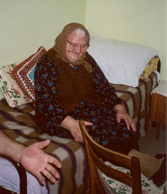 vrouw zit op bed in ouderlingentehuis
